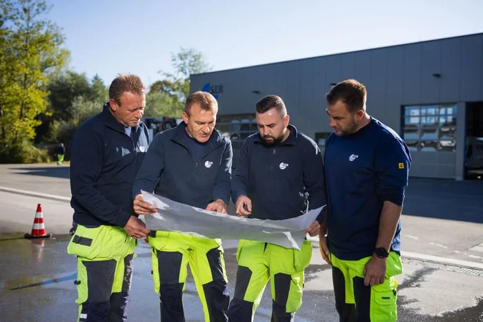 Vier Mitarbeiter eines Wasserbetriebs studieren gemeinsam einen Plan